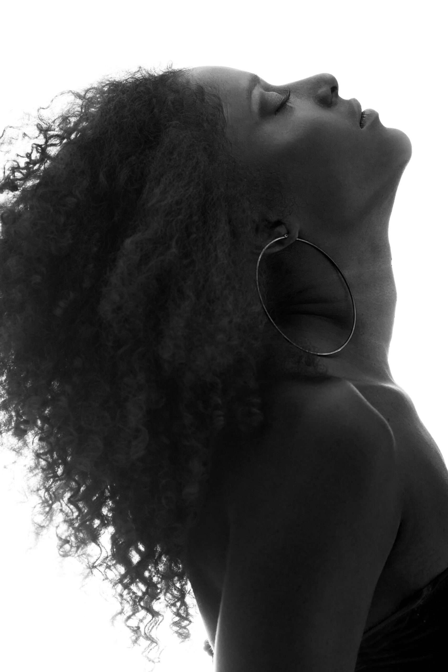Female Posing With Curly Hair and Hoop Earrings | Prick'd Medspa in St. Louis, MO